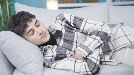 el joven que se estira en el sofá está pensativo y preocupado.