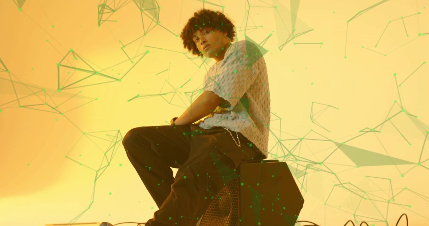 Model in studio tapping foot squatting on speaker and activating polygonal graphics in audio design