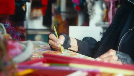 woman using a color pencil to draw a complicated sweater knitting pattern on paper the old fashioned way with colorful yarn everywhere. slow motion sliding shot.