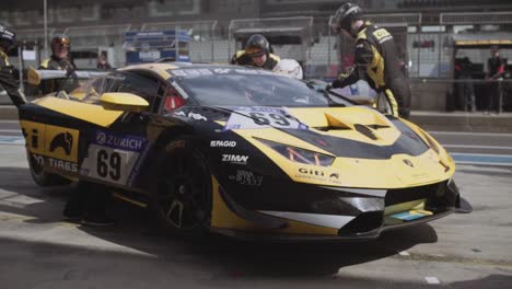 pit crew mechanics preparing and cleaning giti lamborghini huracan race car in pit lane in sunny daylight before the start of the adac nurburgring twentyfour hour race.