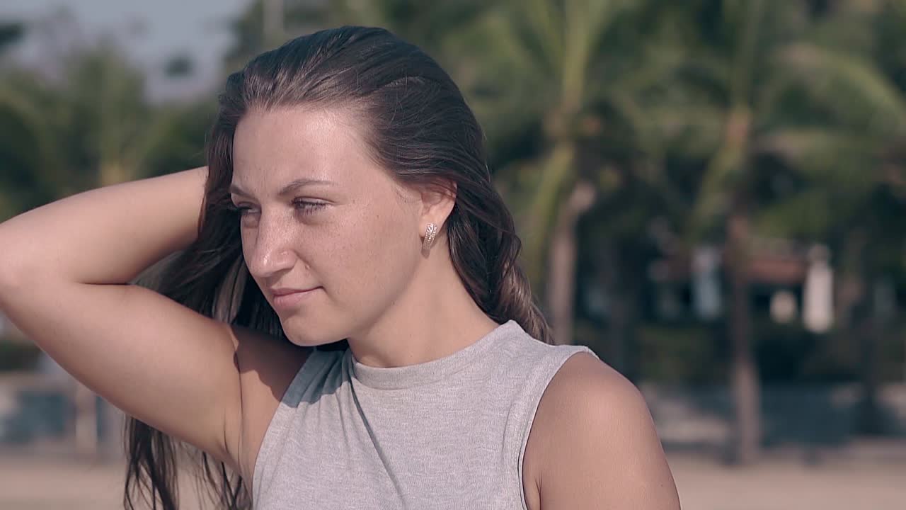 매력적인 여인이 손바닥에 머리카락을 손으로 고정시니다. 느린 동작