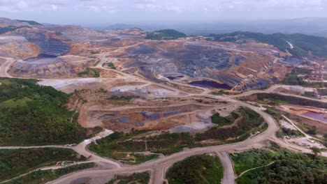 immense pueblo viejo open-pit mine, terraced landscape, winding roads and excavation pits, cotuí, barrick gold, dominican republic. aerial forward