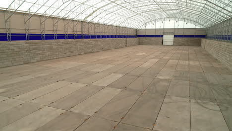 a smooth shot of the interior of a grain warehouse with a with roof and a wooden floor