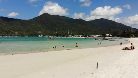 flying close over sandy beach and tourists at ao chaloklum bay in koh phangan, thailand, with a drone