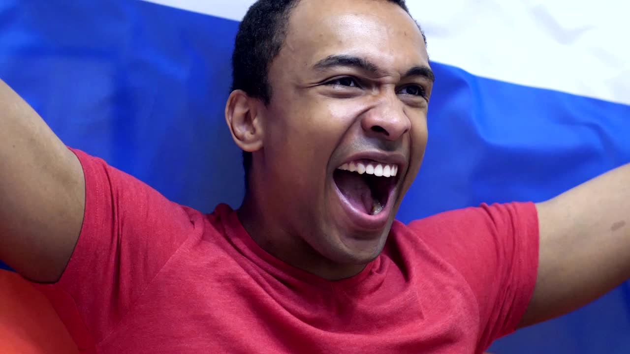 fanático ruso celebrando mientras sostiene la bandera de rusia en cámara lenta
