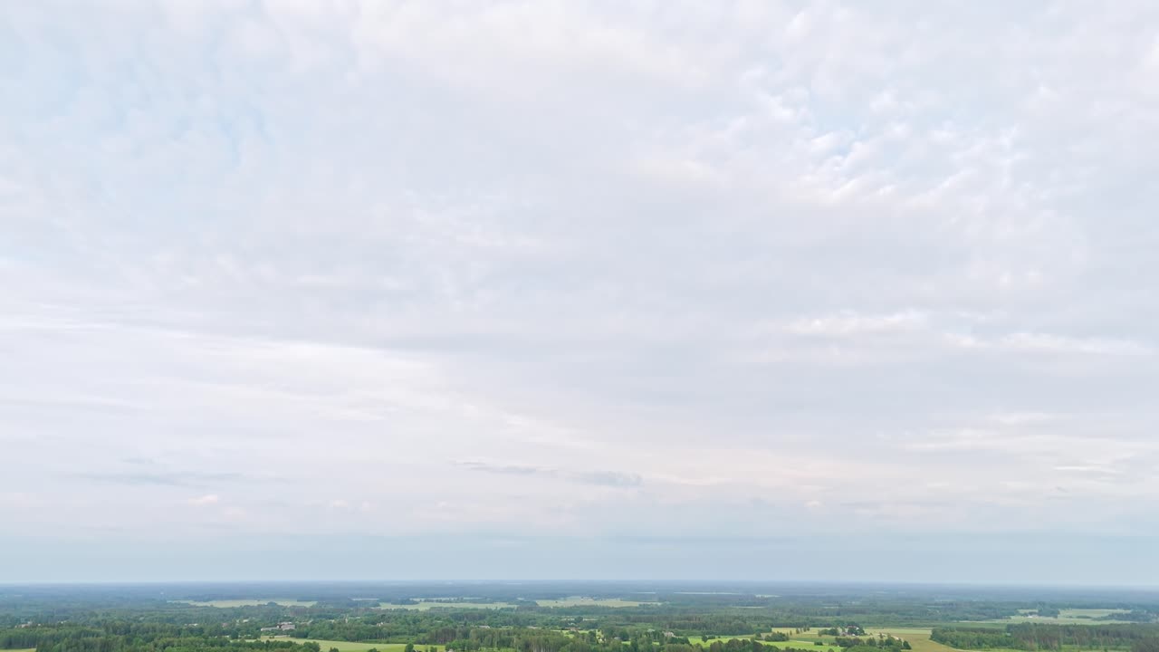 Winding road towards nearby town surrounded by countryside farmland, aerial tilting upward