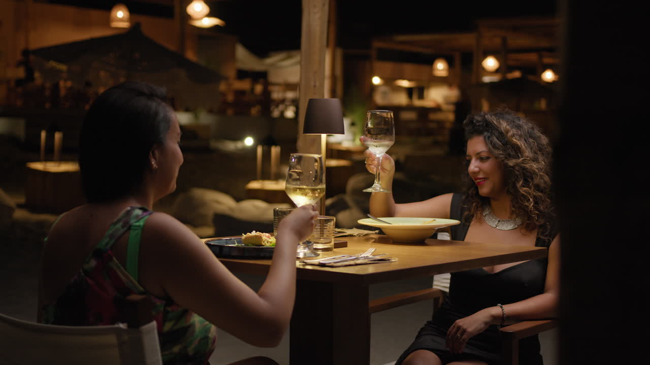 Two Women Cheering With A Glass Of Wine During A Dinner At The Luxury Resort