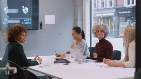 Joven-Empresaria-Liderando-Una-Reunión-Creativa-De-Mujeres-Que-Colaboran-Alrededor-De-Una-Mesa-En-Una-Oficina-Moderna