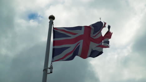 old union jack flag blowing in strong wind against clouds in slow motion