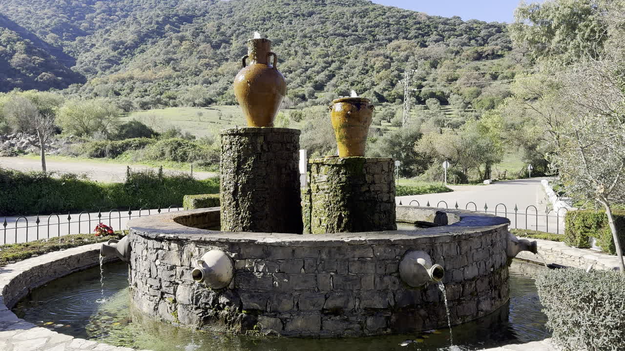 rustic stone fountain with large pots in scenic mountainous area
