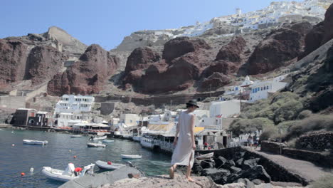 vista de un pequeño puerto pesquero en una isla griega con una mujer que pasea por las rocas