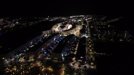 nighttime aerial footage of of phu quoc grand world area with distinctive multi-story buildings lining curving, lavishly illuminated streets, showcasing thoughtful urban planning and vibrant activity.
