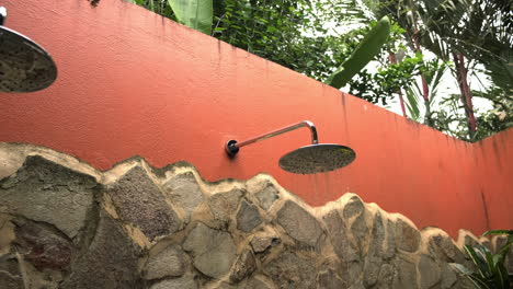 Mujer-Con-Traje-De-Baño-Se-Ducha-Afuera-Rodeada-De-Plantas-De-La-Jungla