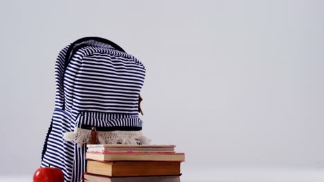 schoolbag, apple and book stack on white background