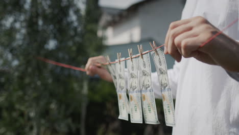 A-man-holds-a-clothesline-in-his-hands,-on-which-banknotes-hang.-Money-laundering-concept.-Side-view