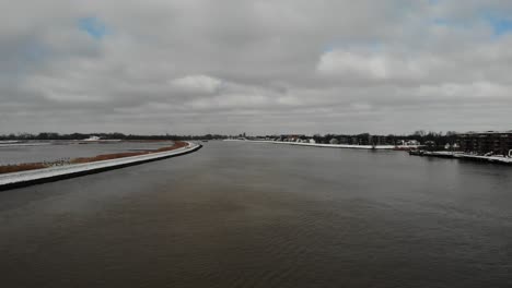 Paisaje-Nublado-Sobre-Un-Canal-Sereno-Con-Un-Buque-De-Carga-Cargado-De-Contenedores-Intermodales-Que-Cruzan-El-Río-Noord-En-Países-Bajos