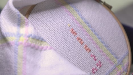 close-up shot of a woman's hand cross-stitching a pattern onto a baby blanket