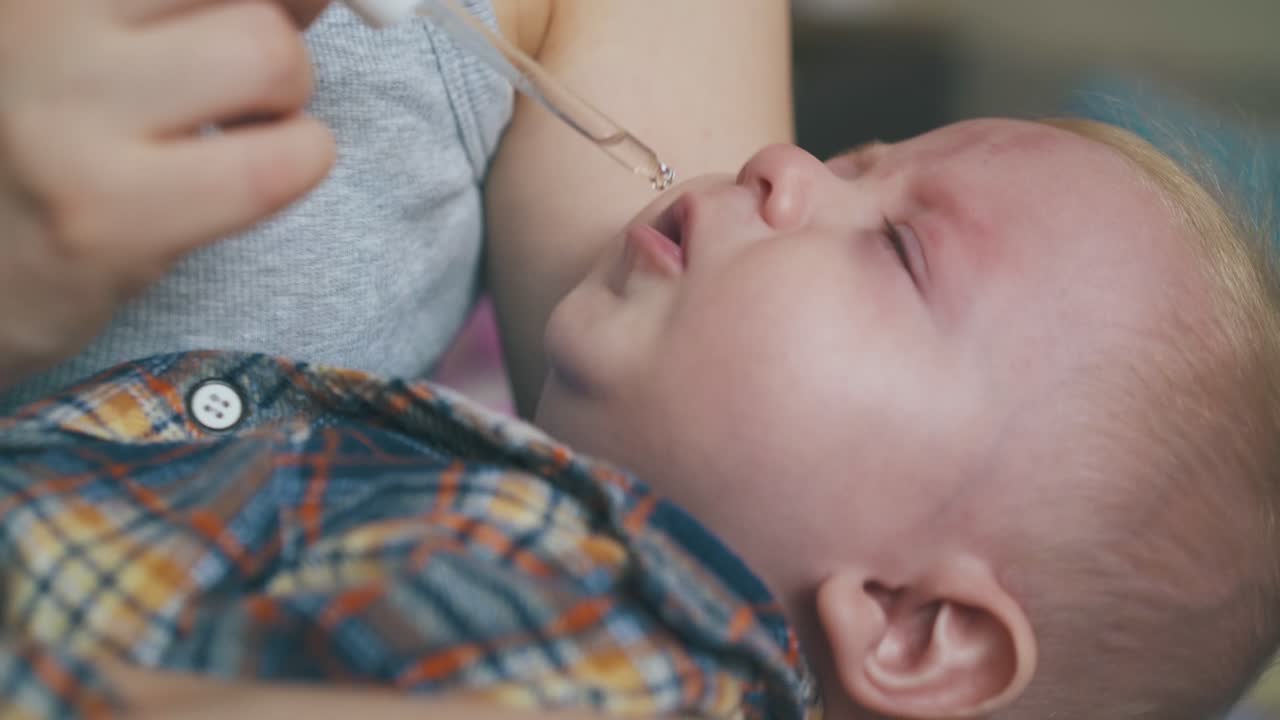 la mamá da la cura del resoplido al bebé con pipeta en la habitación