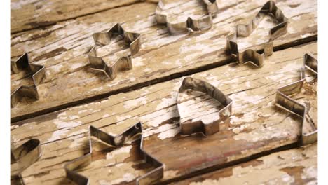 Animation-of-cookie-cutters-on-wooden-background-at-christmas