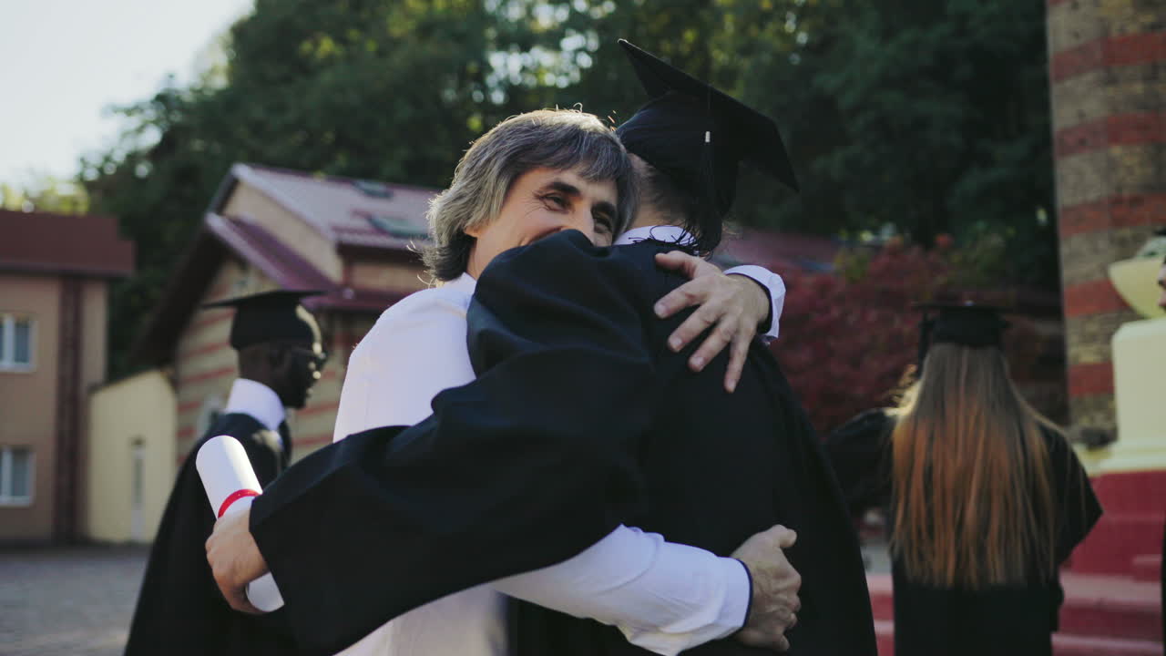Male graduate hugging with his father, dad congratulating his son with a graduation from University