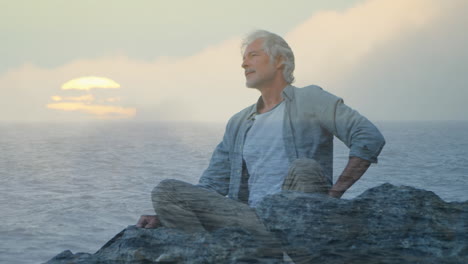 old man sitting on rocks and a view of the sea