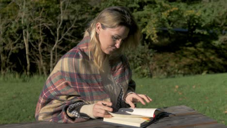 Woman-sits-at-park-bench-to-study-outdoors