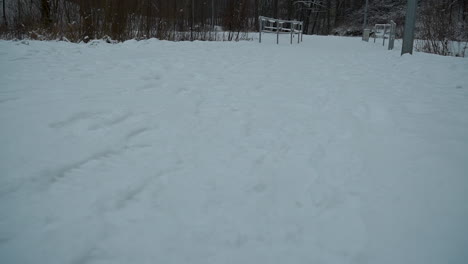 POV-shot-of-person-walking-over-a-field-completly-covered-of-white-snow-landscape