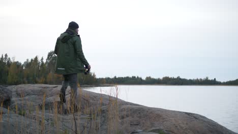 Hiking-man-with-binoculars-watching-birds-from-shoreline-cliff,-Ornithology