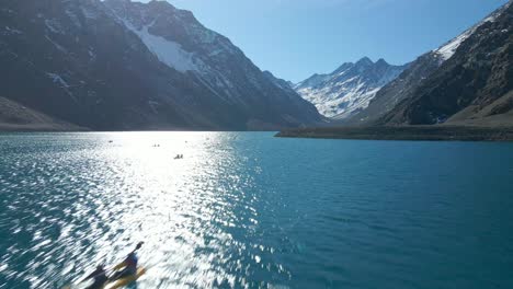 vista aérea de personas en kayaks en la laguna del inca, en los andes chilenos, montañas nevadas en un día soleado en el fondo