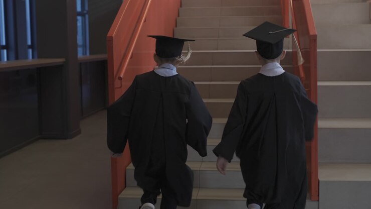 Close up of two kindergarten students running up the stairs at the preschool graduation ceremony