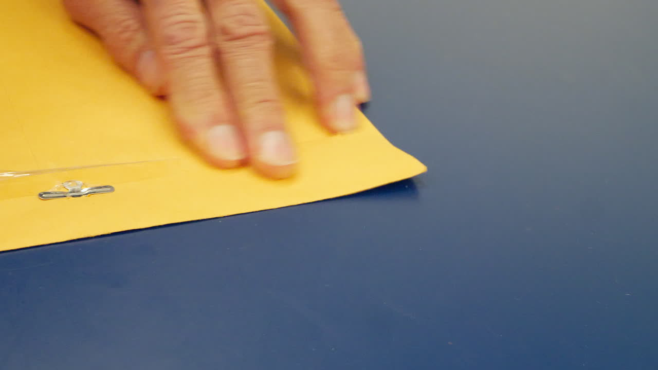 cerrar las manos cerrando un sobre amarillo con un documento importante dentro para ser enviado por correo y entregado