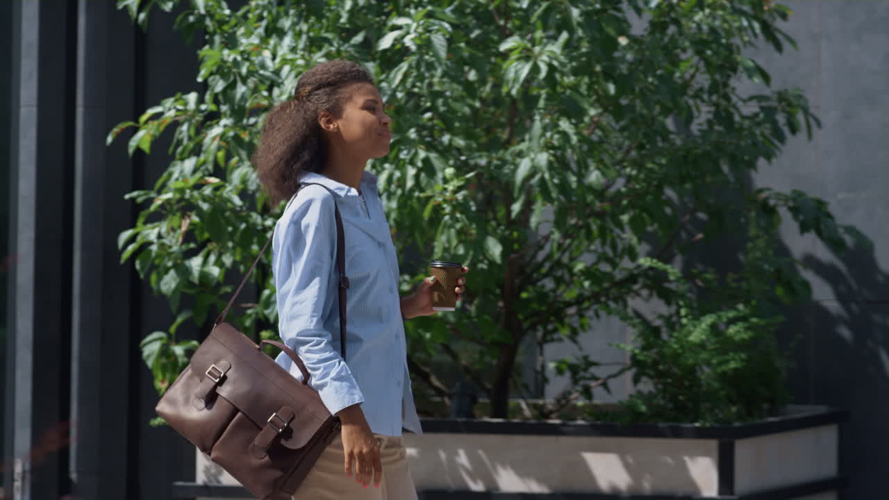 gerente feliz yendo a trabajar sosteniendo una taza de café en un día soleado. distrito del centro.