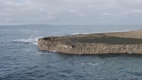 Eine-Landzunge,-Die-Still-In-Einem-Ozean-Aus-Turbulentem-Wasser-Liegt-Und-Gegen-Die-Steilen-Seiten-Kracht-Und-Spritzt