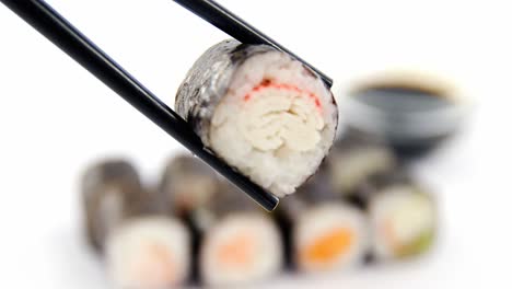 Maki-sushi-being-held-in-wooden-chopsticks