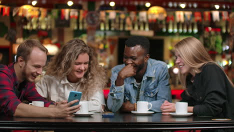 african-american man with a girl looking at a smartphone and talking while sitting in a coffee and drinking coffee friends a group of people in a restaurant.