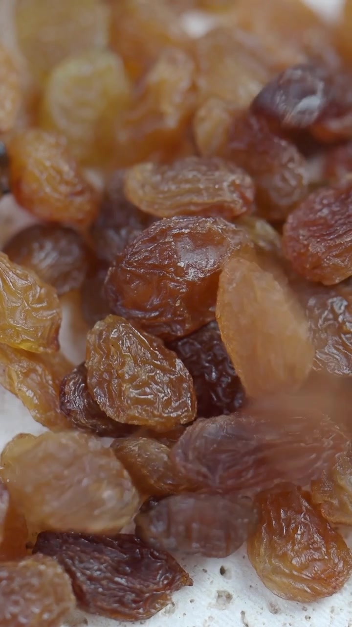 Gros plan sur des raisins secs dorés qui tombent et s'empilent