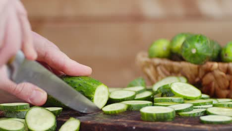 male hand with a knife cut the cucumber into smooth round pieces.