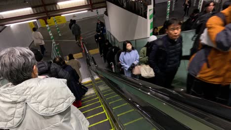 commuters riding an escalator in a busy station