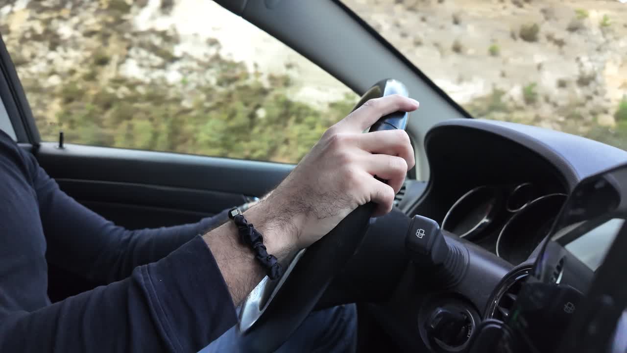 Slow-motion close-up of a driver’s hand firmly holding the steering wheel