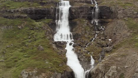 majestuosa cascada fluye por un acantilado rocoso en el paisaje salvaje de islandia, aéreo