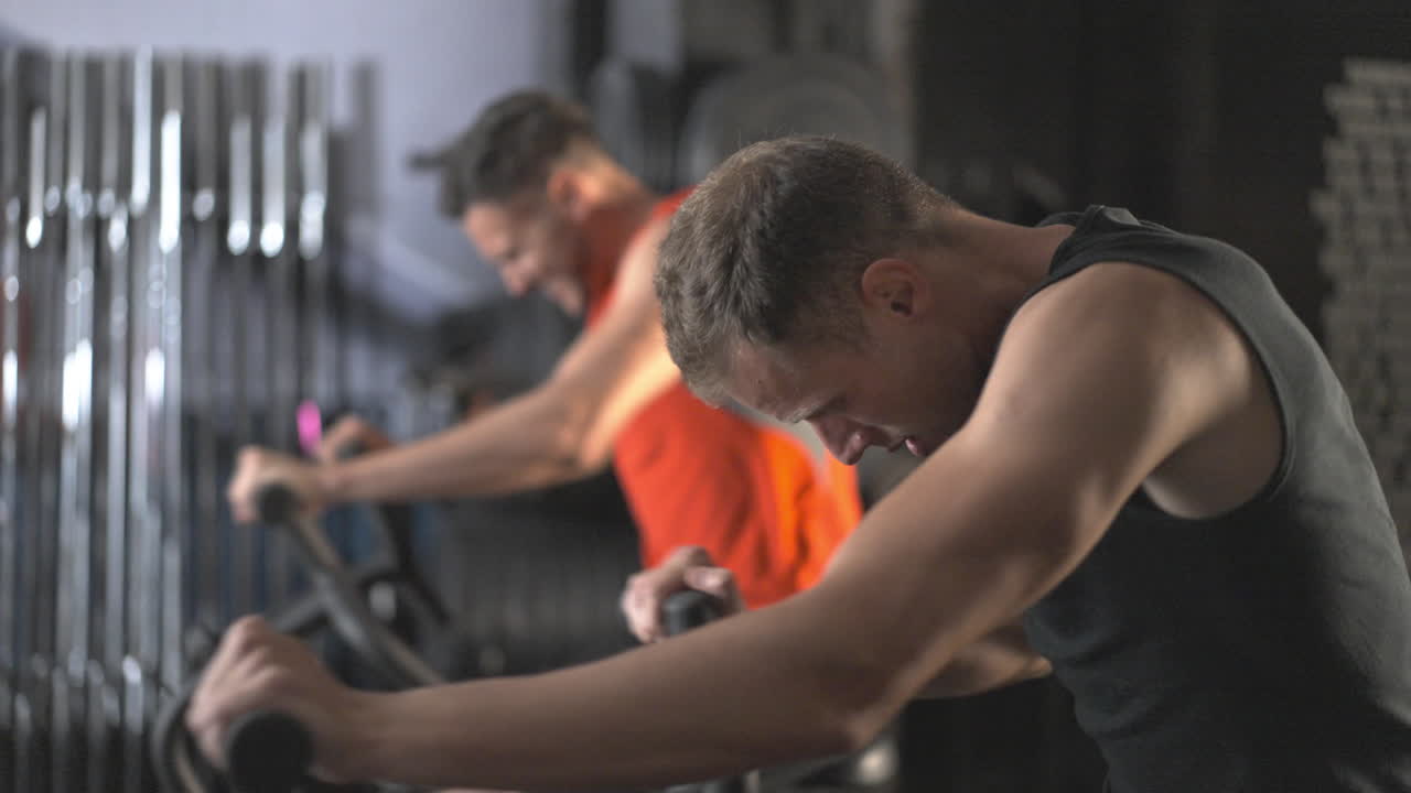 Two men working out on stationary bikes in a gym