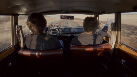happy couple driving along rural road in vintage car