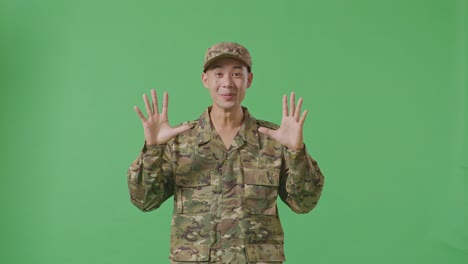 asian man soldier smiling and saying wow while standing in the green screen background studio