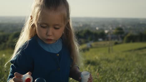 cute little caucasian girl playing with bubbles at the meadow.