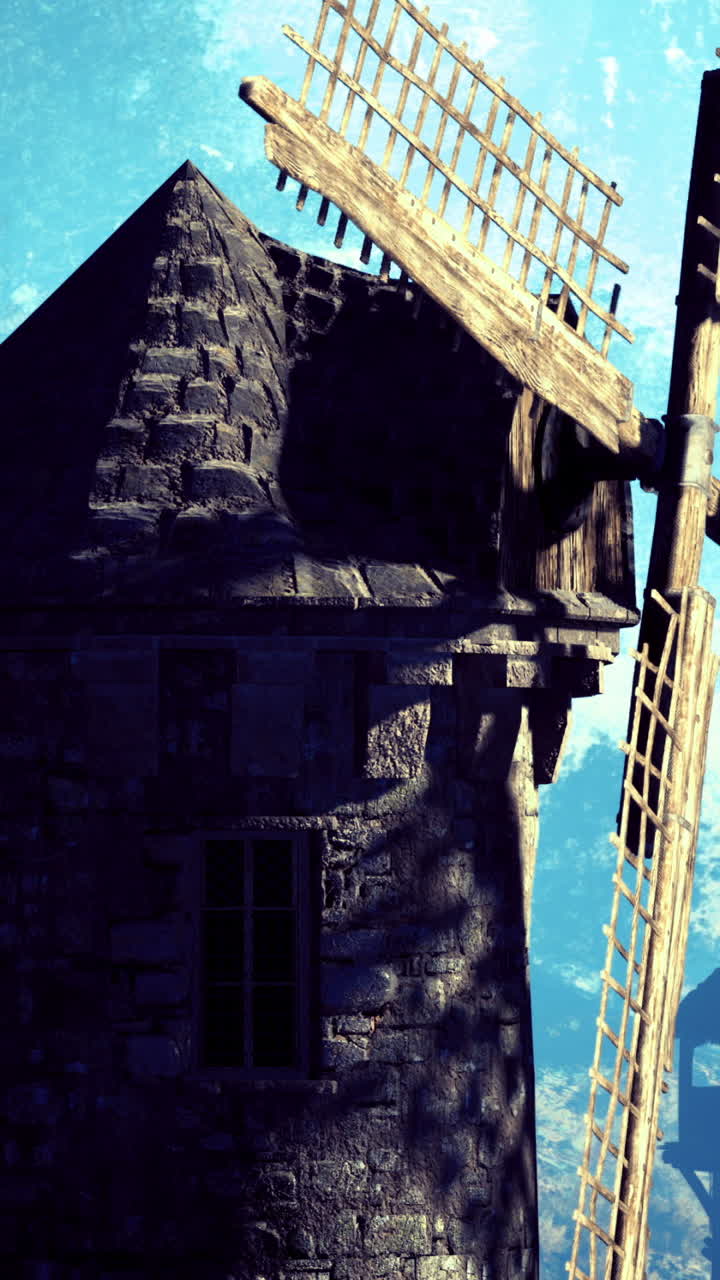 Molino de viento histórico contra un sereno telón de fondo montañoso durante el día.