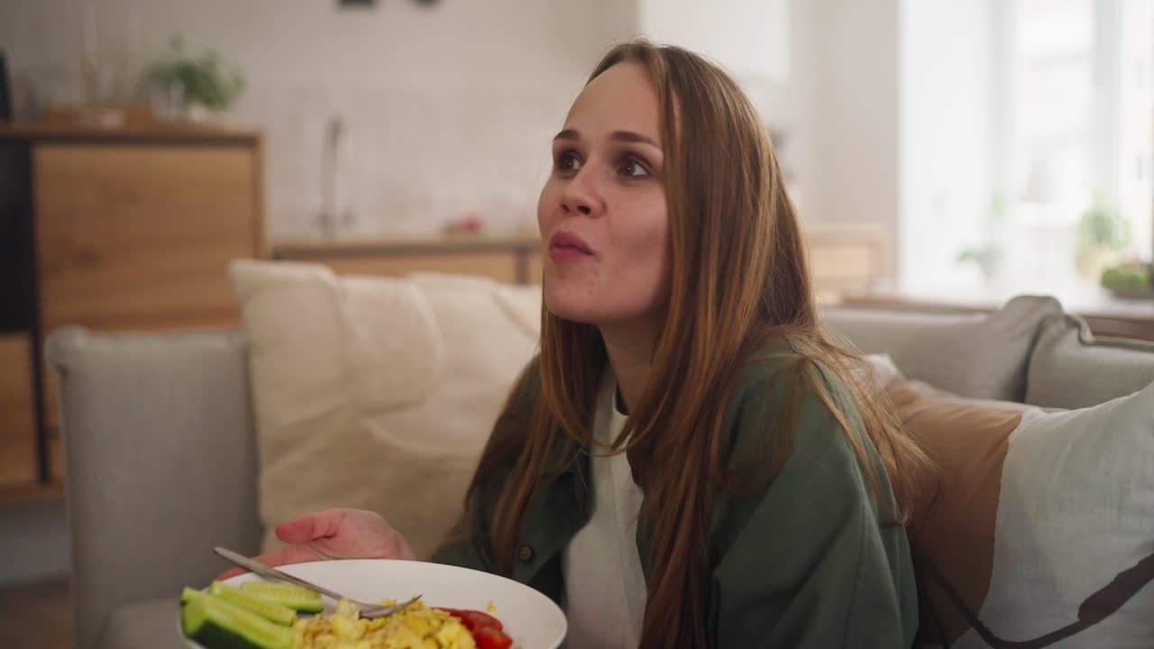 mujer tomando el desayuno en el sofá