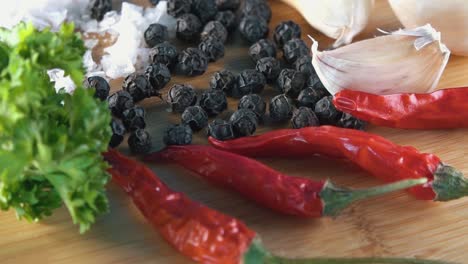 Pepper-Salt-Chilli-and-Parsley-Ingredients-Rotating-on-a-Bamboo-Board