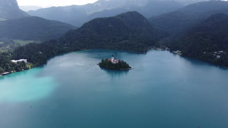 toma cinematográfica de drones de la isla de bled con la iglesia y la cordillera de eslovenia en el fondo