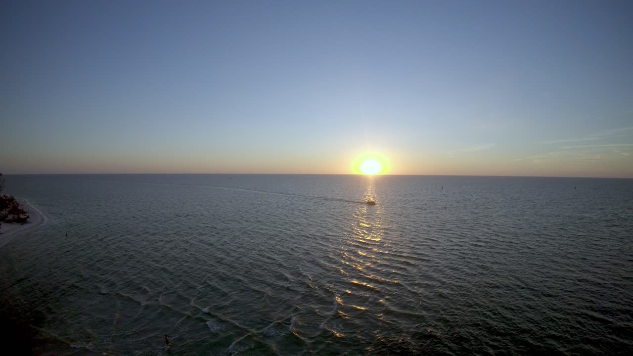 플로리다 주 네이플스 (naples) 의 클램 패스 해변에서 물을 건너는 배의 4k 드론 영상입니다.