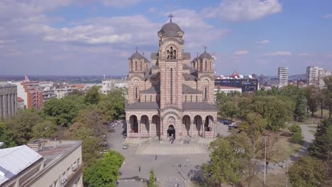 Descending-4k-aerial-revealing-shot-of-St-Mark-Church-in-Tasmajdan-park,-Belgrade